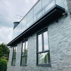 Modern home exterior walls with glass balcony, dark grey windows, clad with a silver grey split-face mosaic wall tiles for a stylish textured look.